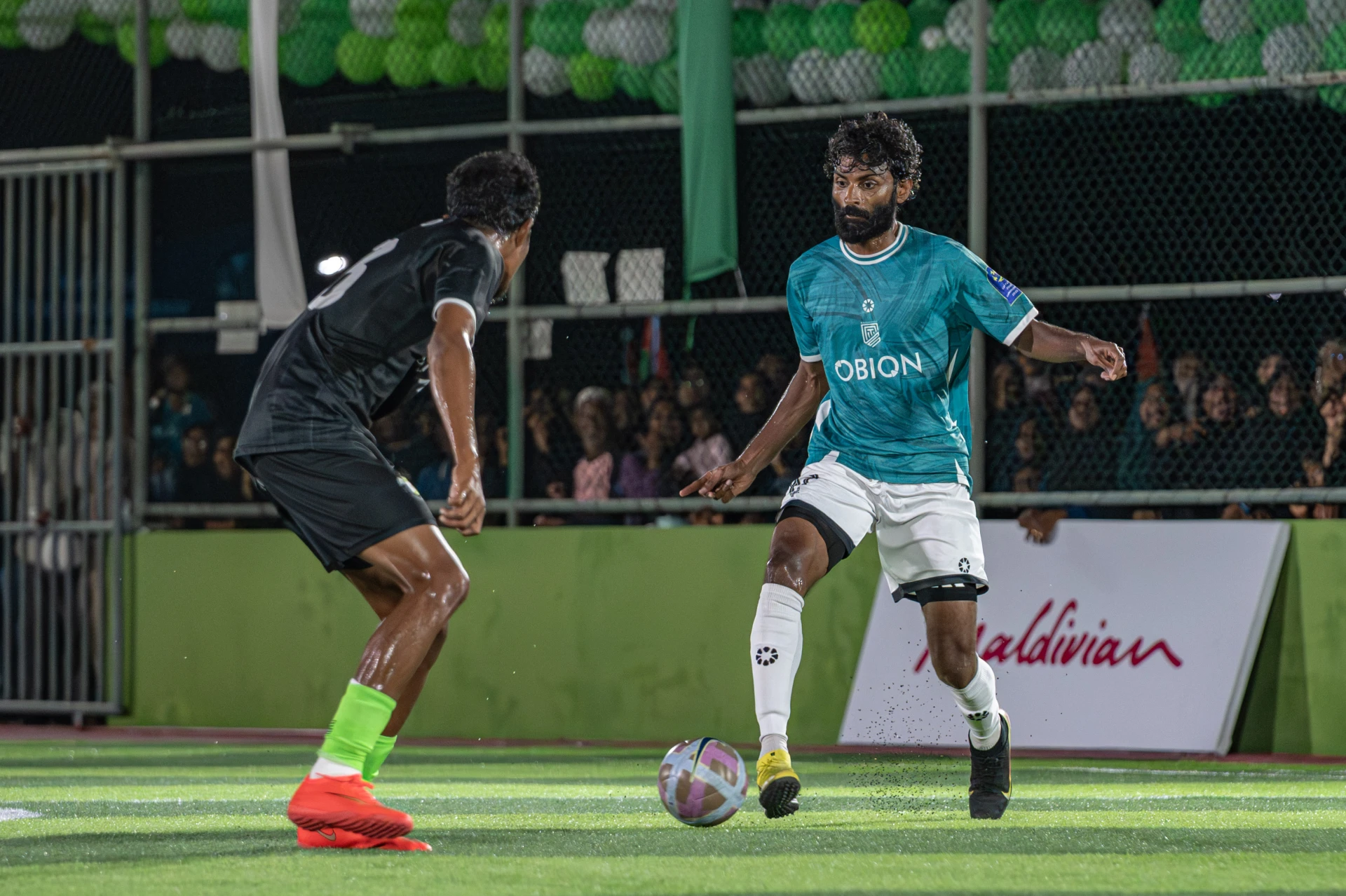ފައިނަލް މެޗުގައި ނައިވާދޫގެ އަބްދުﷲ ޝާފިއު (ޝާއްޕެ) ބޯޅަ ހިފައިގެން ދާއިރު އިހަވަންދޫ ކުޅުންތެރިޔާ ސަމާލުވެގެން. ފޮޓޯ: ކްލަބް މޯލްޑިވްސް